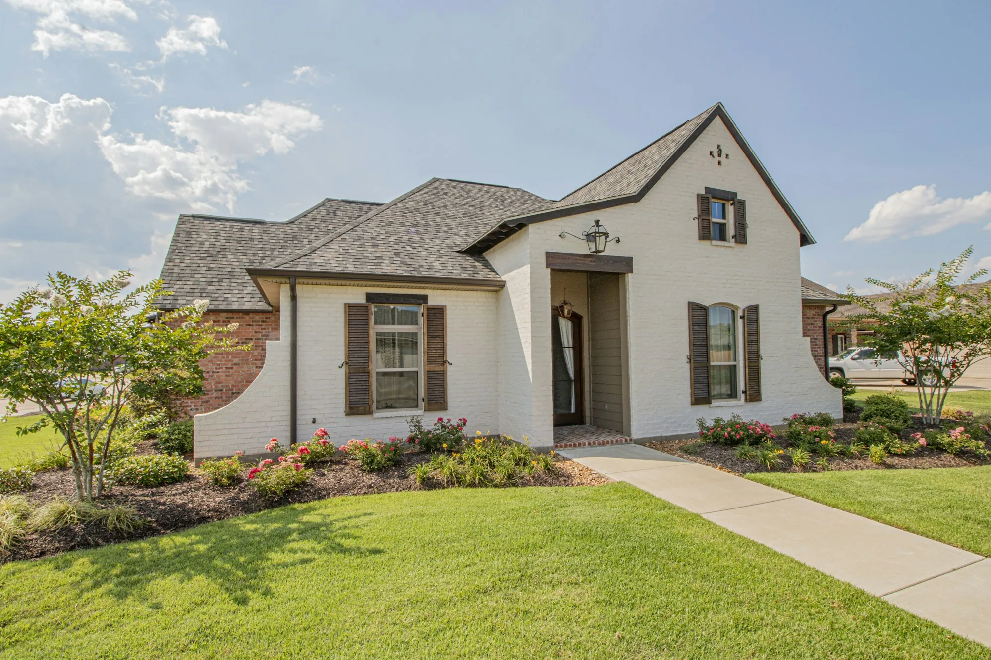 Cream French country home with a hipped shingle roof and green lawn