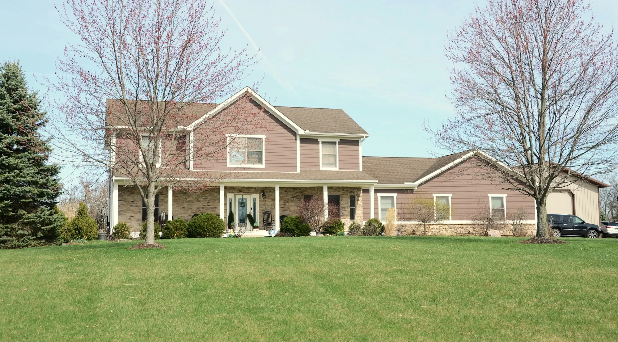 Two-story brick and siding home with a wide green front lawn