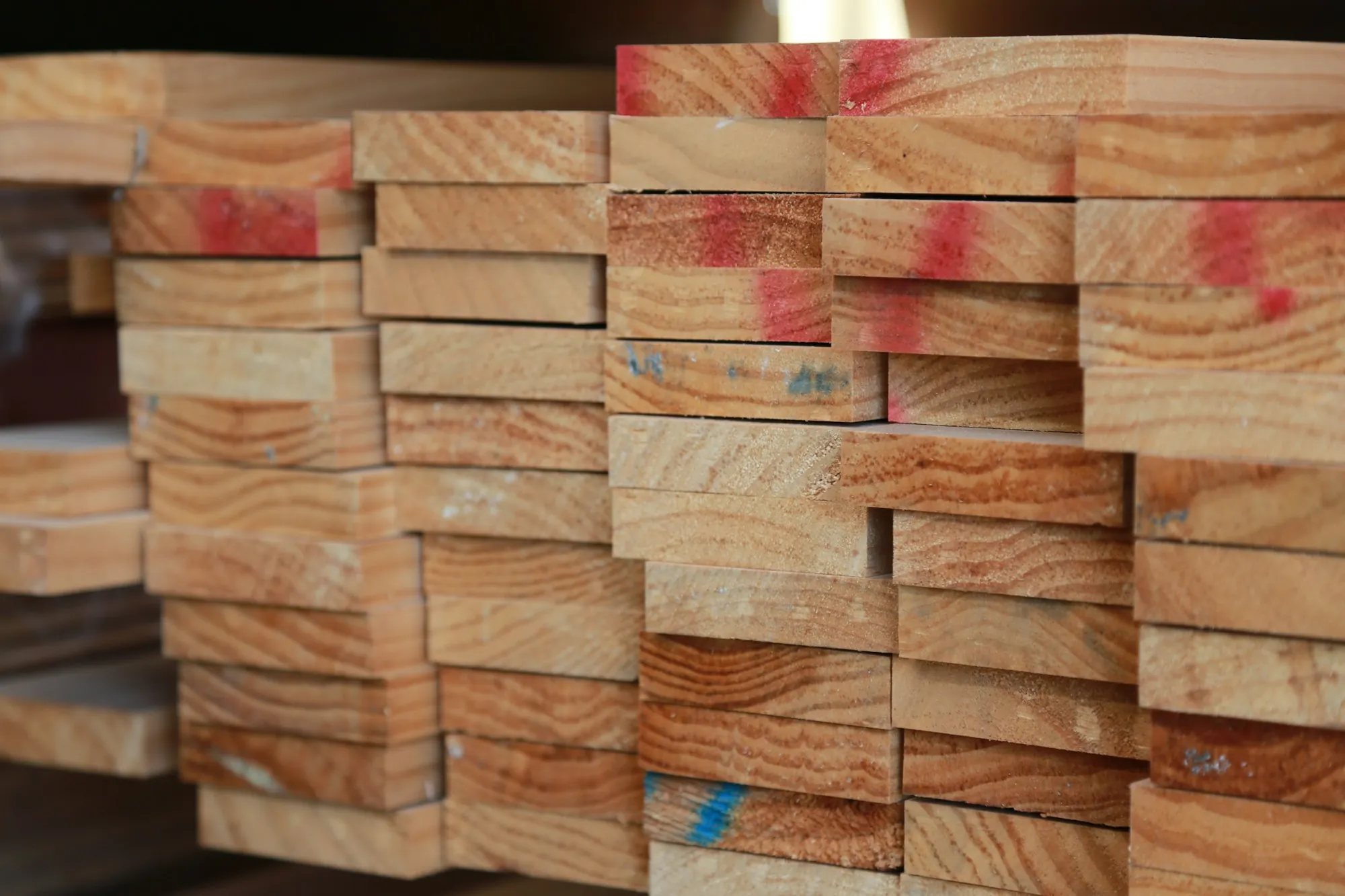 Stack of fresh-cut lumber boards with marked ends